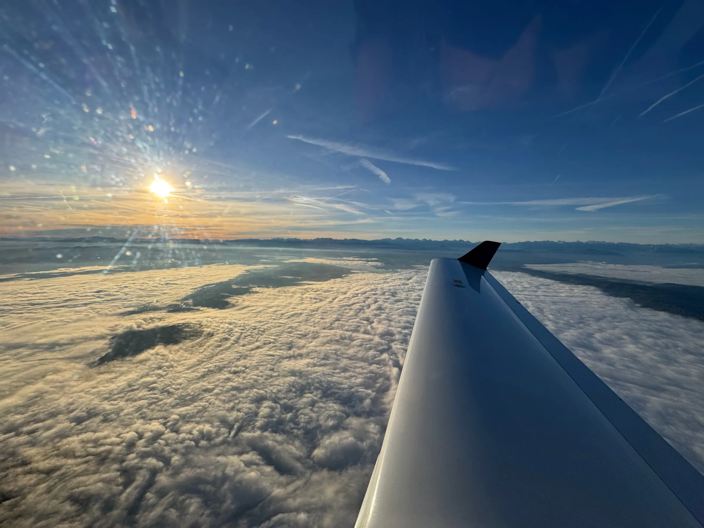 Sunshine above a blanket of cloud seen over the aircraft wing