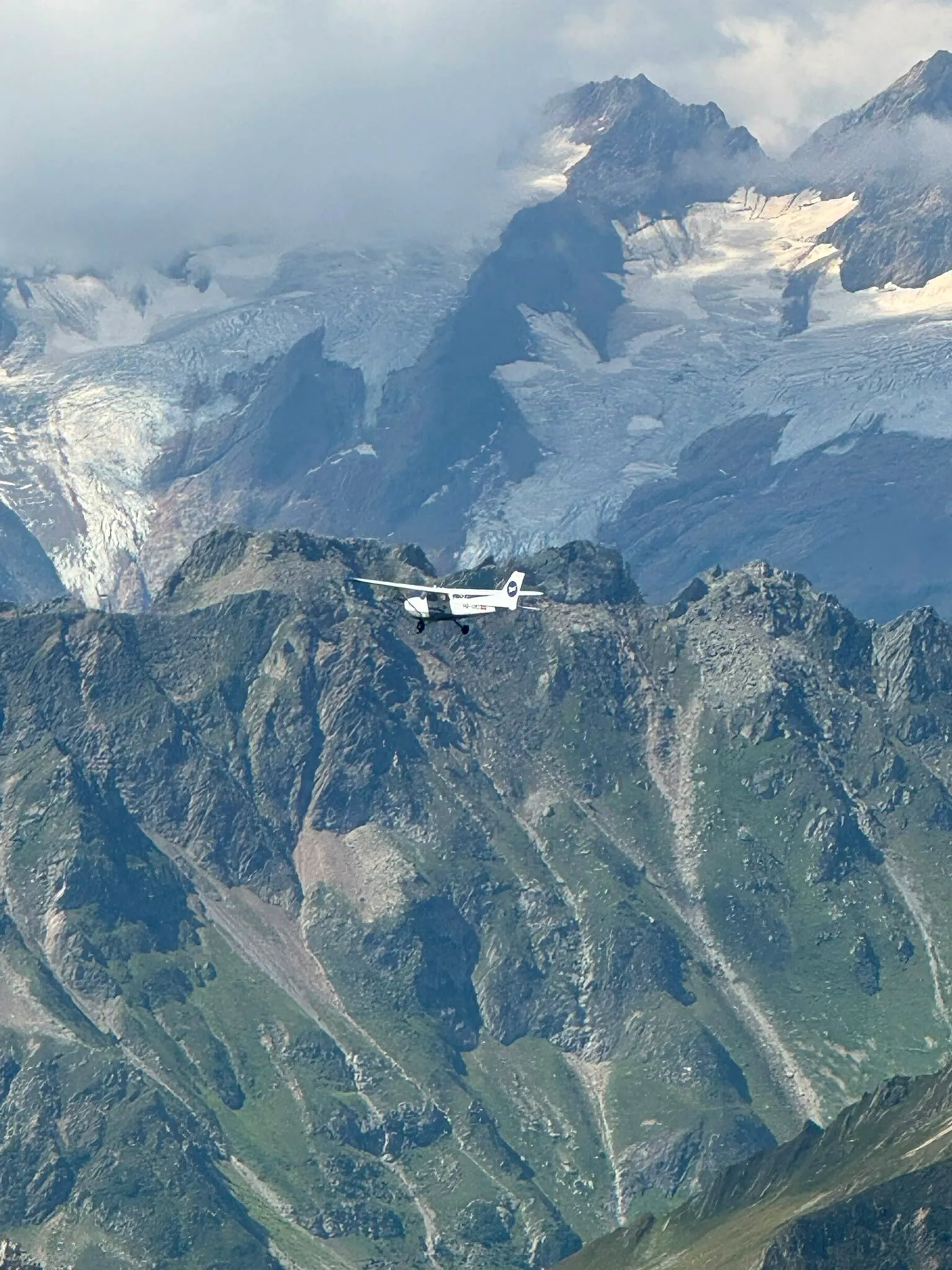 Light aircraft flying past a glaciated alpine peak