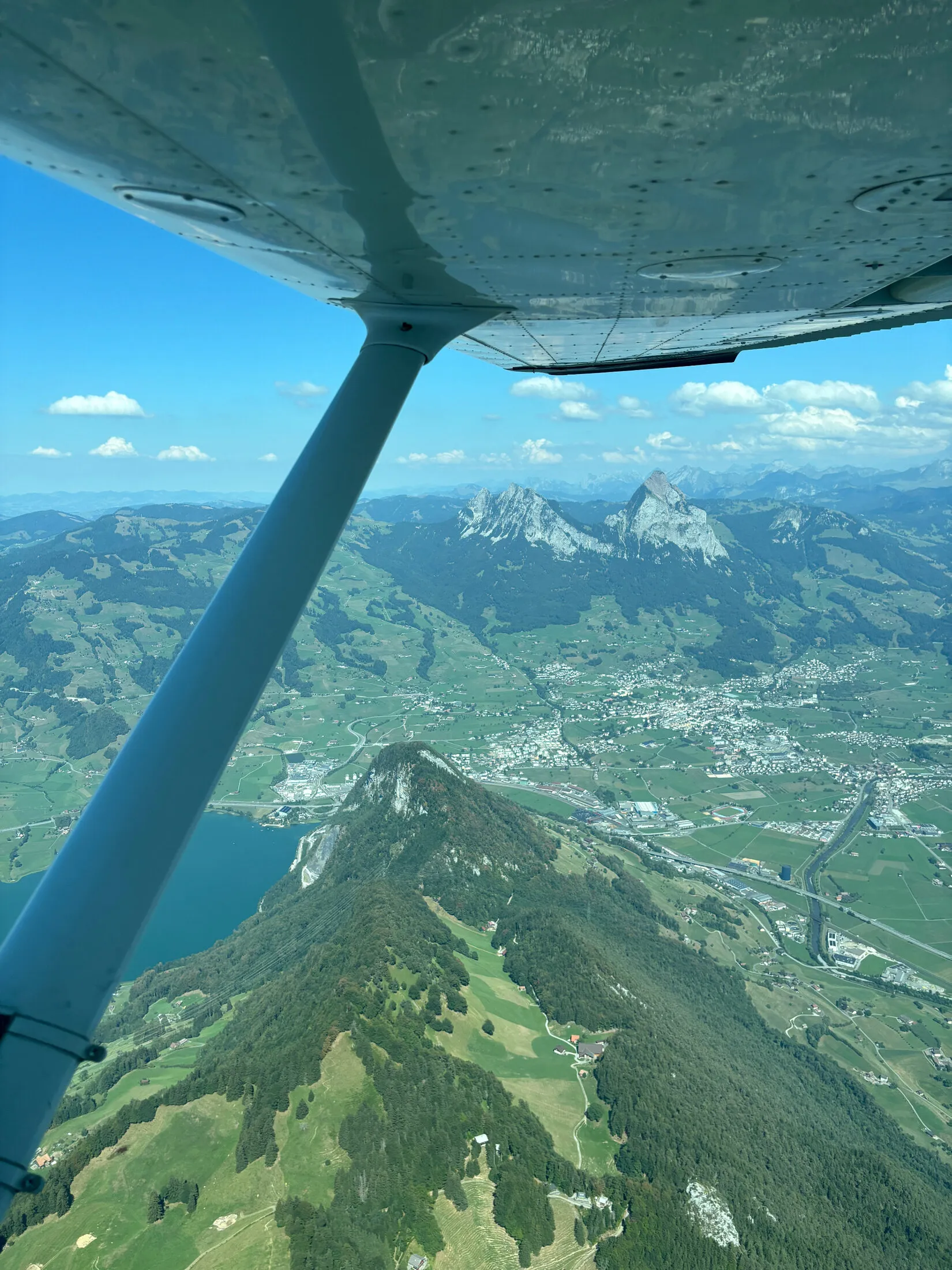 Aircraft wing strut over a lake with the Mythen peaks