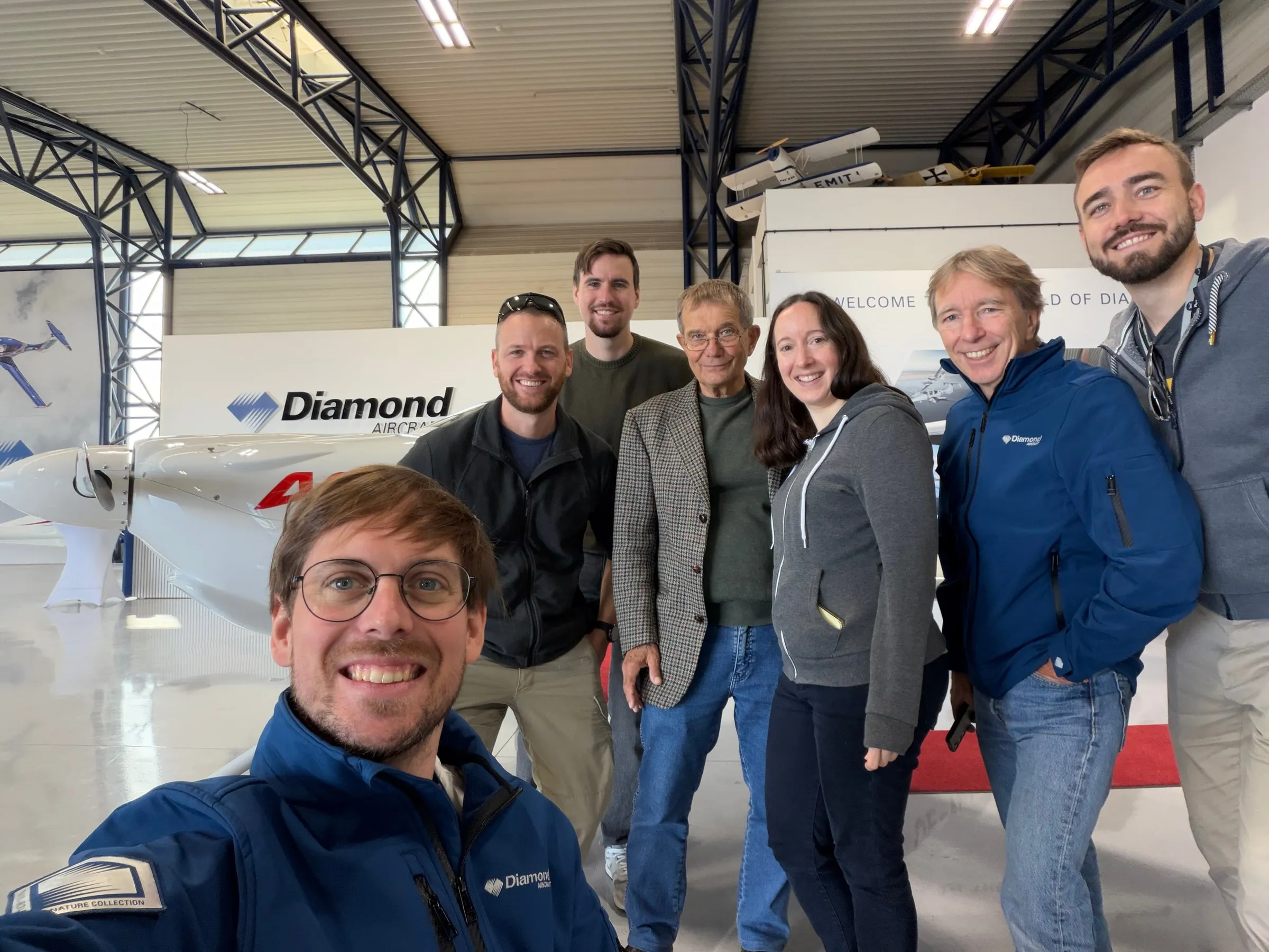 The visiting group taking a photograph together inside the Diamond Aircraft hangar