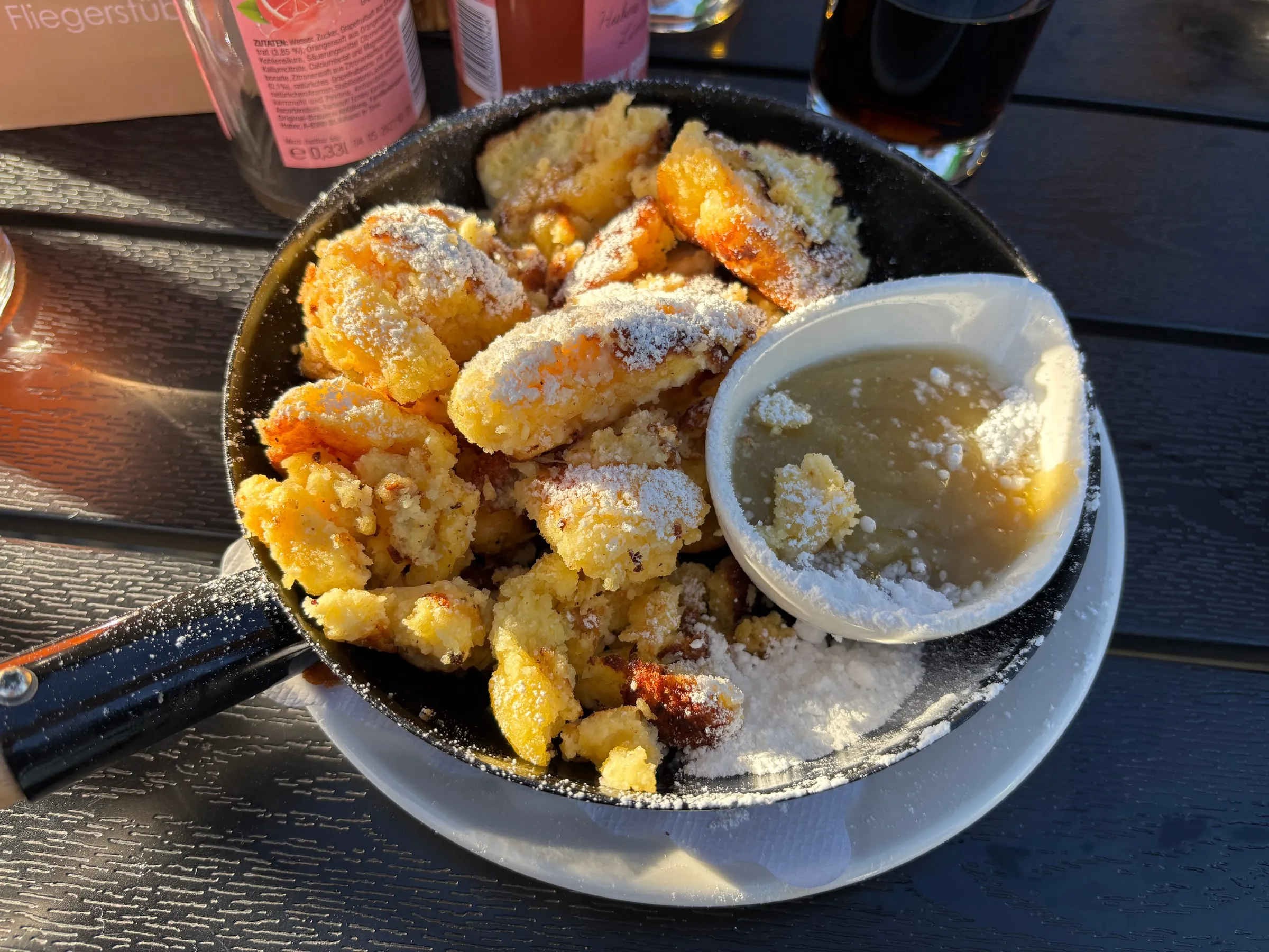 A pan of golden Kaiserschmarrn dusted with icing sugar and served with apple sauce